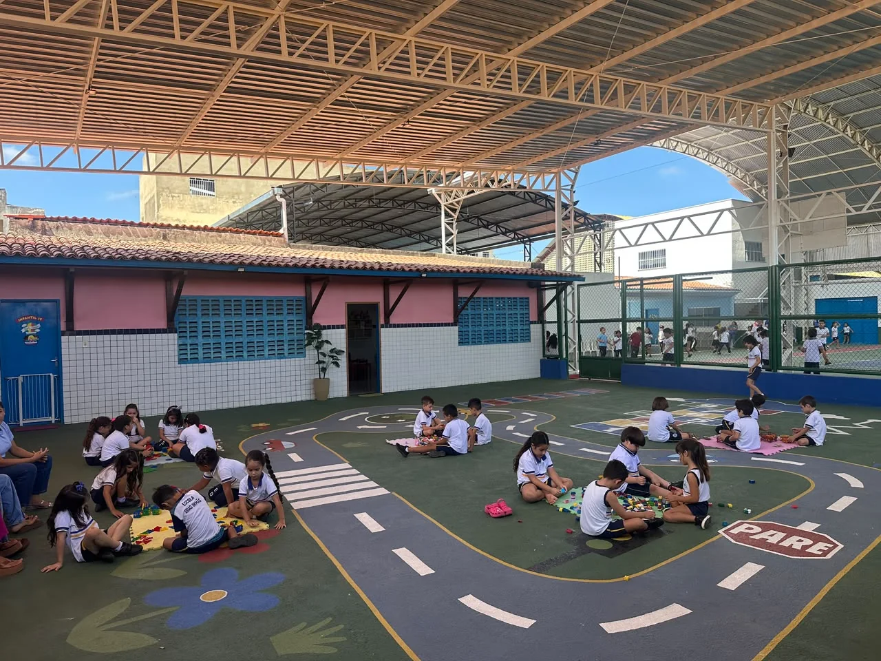Crianças da Educação Infantil participando de brincadeiras e atividades em grupo no pátio coberto da escola