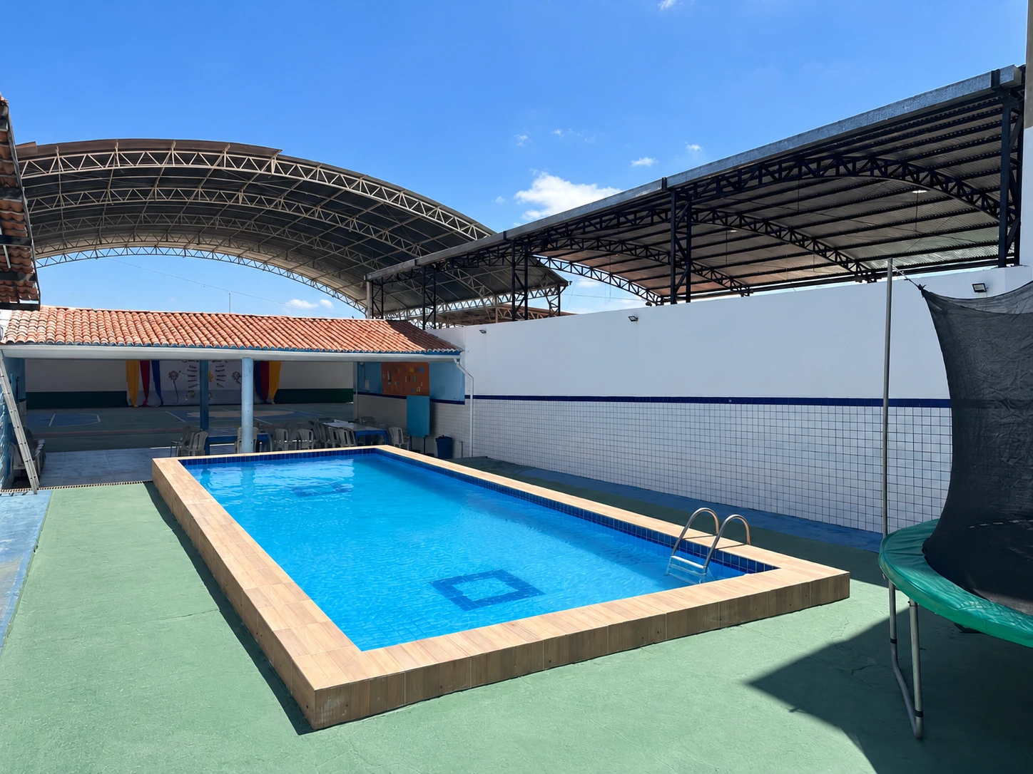 Área da piscina da Escola Duas Irmãs, com piscina azul e cobertura de áreas adjacentes