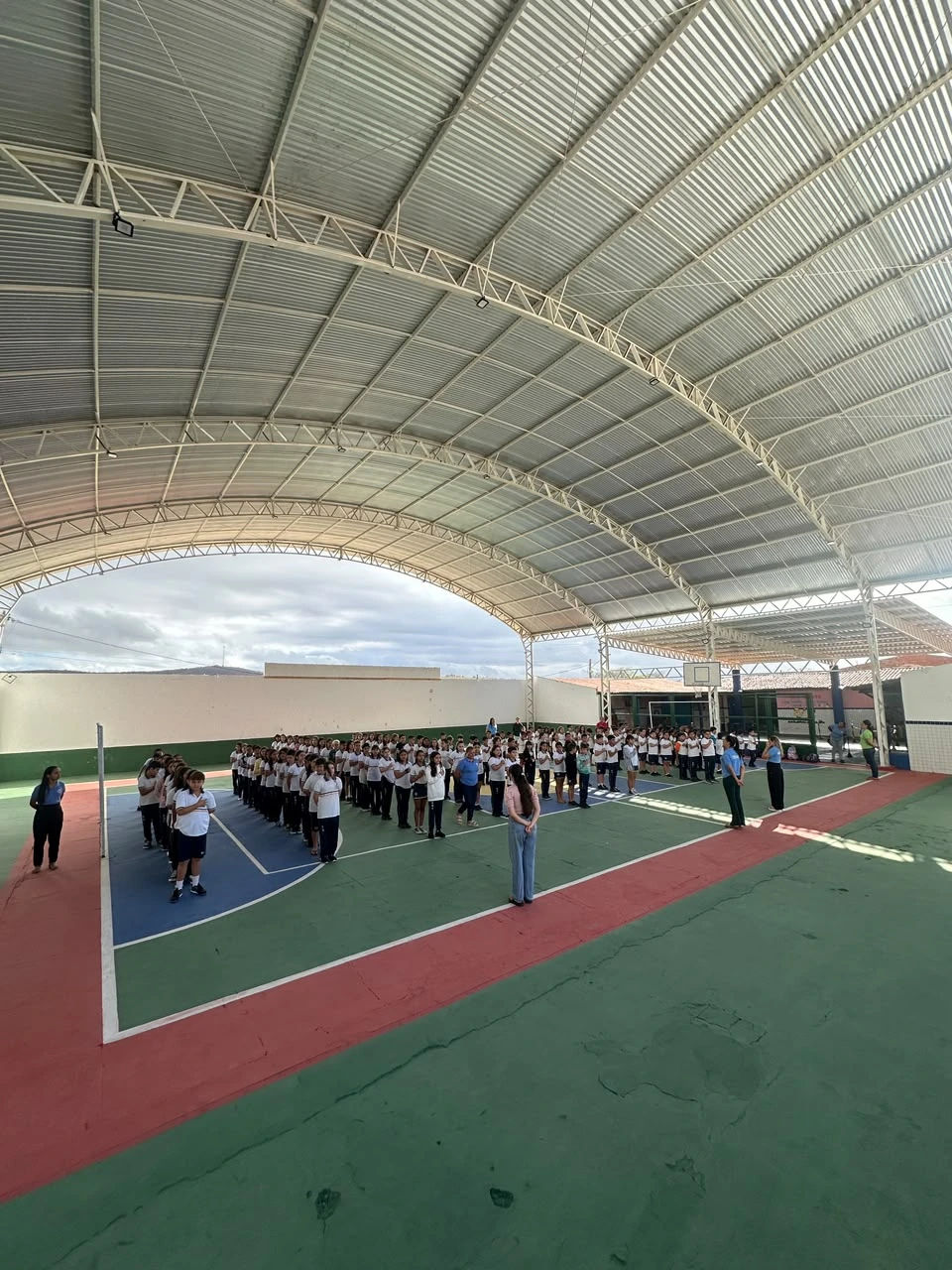Visão ampla da quadra da Escola Duas Irmãs, mostrando a grande cobertura e estudantes reunidos para uma atividade